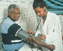 photograph of a young woman doctor taking an older man's blood pressure