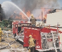 photograph of fire fighters hosing down a fire with water from a fire truck