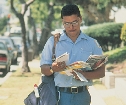 photograph of a male postal carrier delivering mail