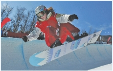 Tricia Byrnes jumps in the air as she competes in a snowboarding event.