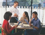 photograph of a family at a restaurant table, waiter taking their order