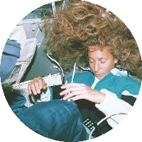 photograph of a female astronaut sleeping in the space shuttle