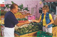 This woman is the first customer. She buys two heads of broccoli for $1.98.