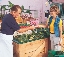 photograph of a woman and a man at a fruit and vegetable stand