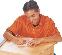 photograph of a teenage boy sitting at a desk writing