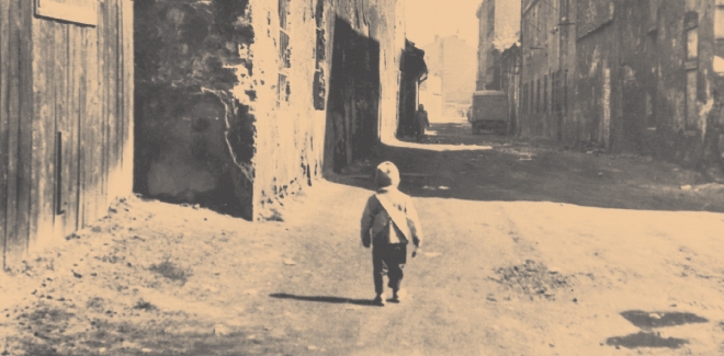 photograph of a child walking down the street of an empty, ruined town