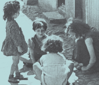 photograph of four children playing on a sidewalk