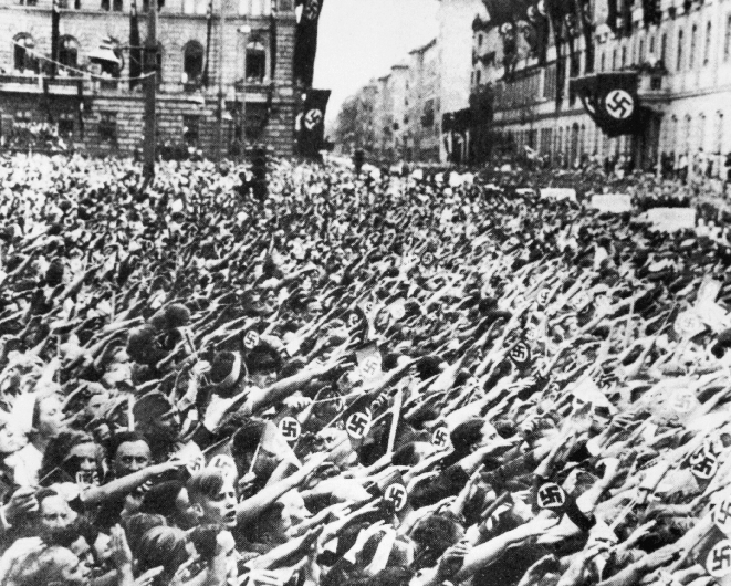 photograph of German Nazis gathered in a town square with Nazi flags hanging