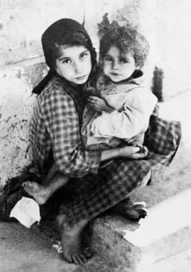 photograph of a young girl holding a little girl on her lap