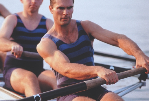 photograph of two muscular men rowing a boat