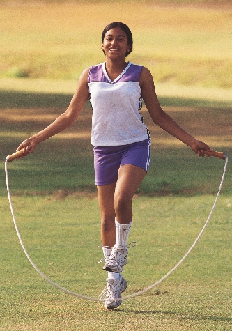 photograph of a young woman skipping rope on a lawn