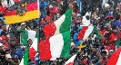 Photograph of a crowd scene with people waving flags from various countries.