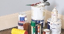 Photograph of several paint cans, other containers, and paintbrushes on the floor