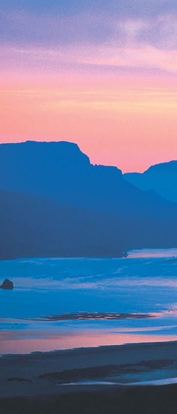 Photograph of the Columbia River in Oregon with mountains in the distance. A boat is on the river.