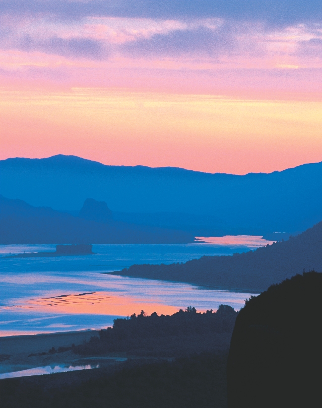 Photograph of the Columbia River in Oregon with mountains in the distance. A boat is on the river.