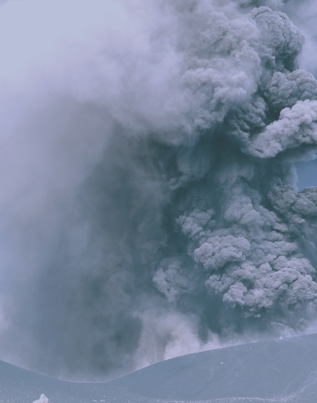 Photograph of grey ash rising into the air and filling the sky