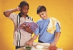 Photograph of two boys with ingredients. One boy looks at the recipe book and is scratching his head.