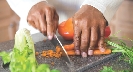 Photograph of a chef's hands cutting carrots with a knife