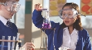 Photograph of two students wearing goggles and working with beakers in a lab