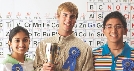 Photograph of three students wearing ribbons they have won at a science fair