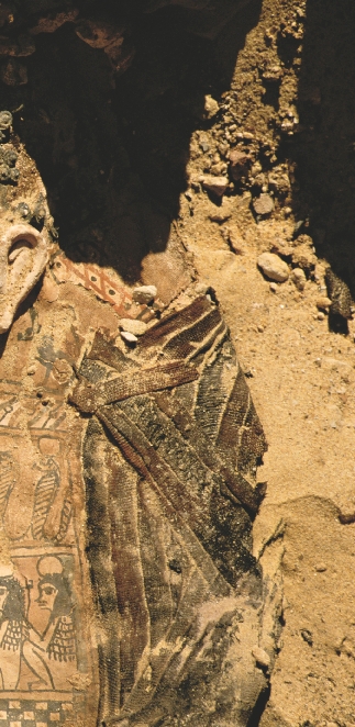 Photograph of someone using a brush to clean sand off an ancient Egyptian carving buried in sand