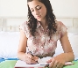 Photograph of a young woman writing in a book (journal)