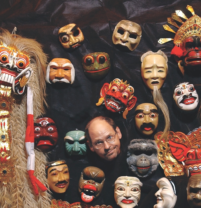 The author poses with some of the masks from his collection.