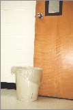 Photograph of a wastebasket by a door