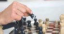 Photograph of a hand moving a chess piece on a chess board