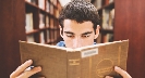 Photograph of a teenage boy at a library, reading intensely