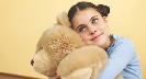 Photograph of a girl hugging her stuffed toy bear