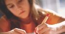 Photograph of a girl writing something on paper