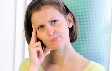 Photograph of a woman with her index finger placed to her head and thinking