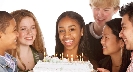 Photograph of smiling people around a birthday cake with candles