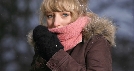 Photograph of a woman pulling her scarf up to cover her mouth on a cold day