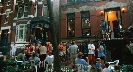 Photograph of people in a city environment standing outside apartment buildings