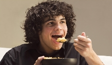 Photograph of a teenage boy eating a bowl of cereal