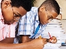 Photograph of two boys writing on paper