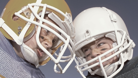 Photograph of a close up of two young boys wearing football helmets