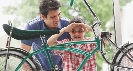 Photograph of a boy with a man looking at a bicycle in a store window