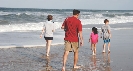 Photograph of people walking along the shore of a beach