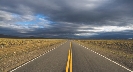 Photograph of a straight highway that seems to meet the horizon far away