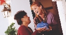 Photograph of one woman handing another a casserole dish