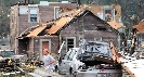 Photograph of a badly damaged home and car