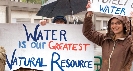 Photograph of someone with sign that reads “Water is Our Greatest Natural Resource”