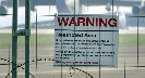 Photograph of a fence with a warning sign on it saying “restricted area”