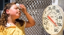 Photograph of a thermometer showing 110 degrees as girl wipes brow with a tissue