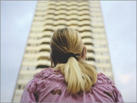 Photograph of a girl looking up at a very tall building