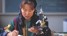 Photograph of a girl looking at a slide near a microscope