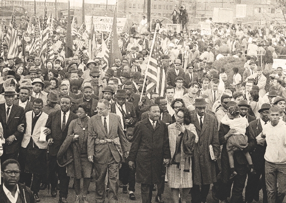 Black and white photograph showing Martin Luther King, Jr and others in a crowd walking